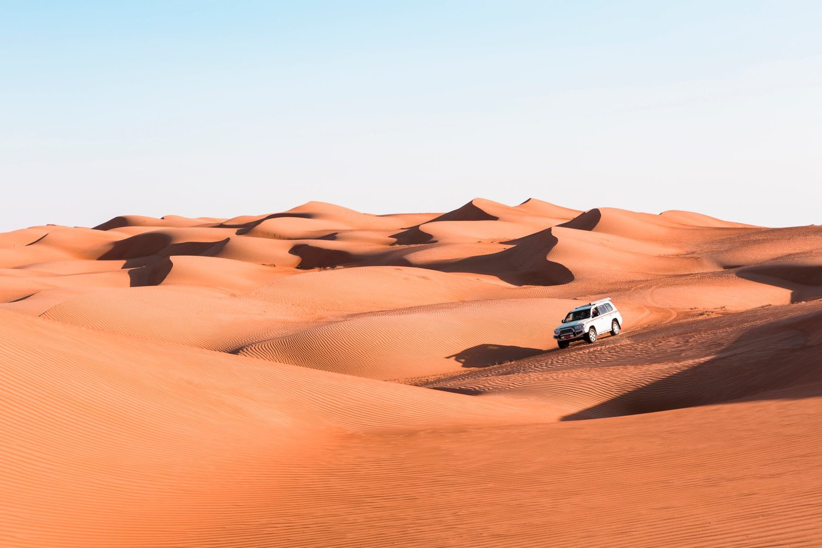 SUV carving through golden Dubai sand dunes at sunset