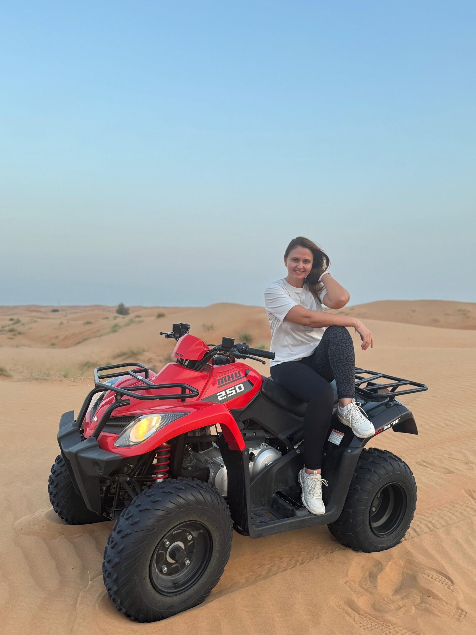 Rider posing with KYMCO 250cc quad at golden hour